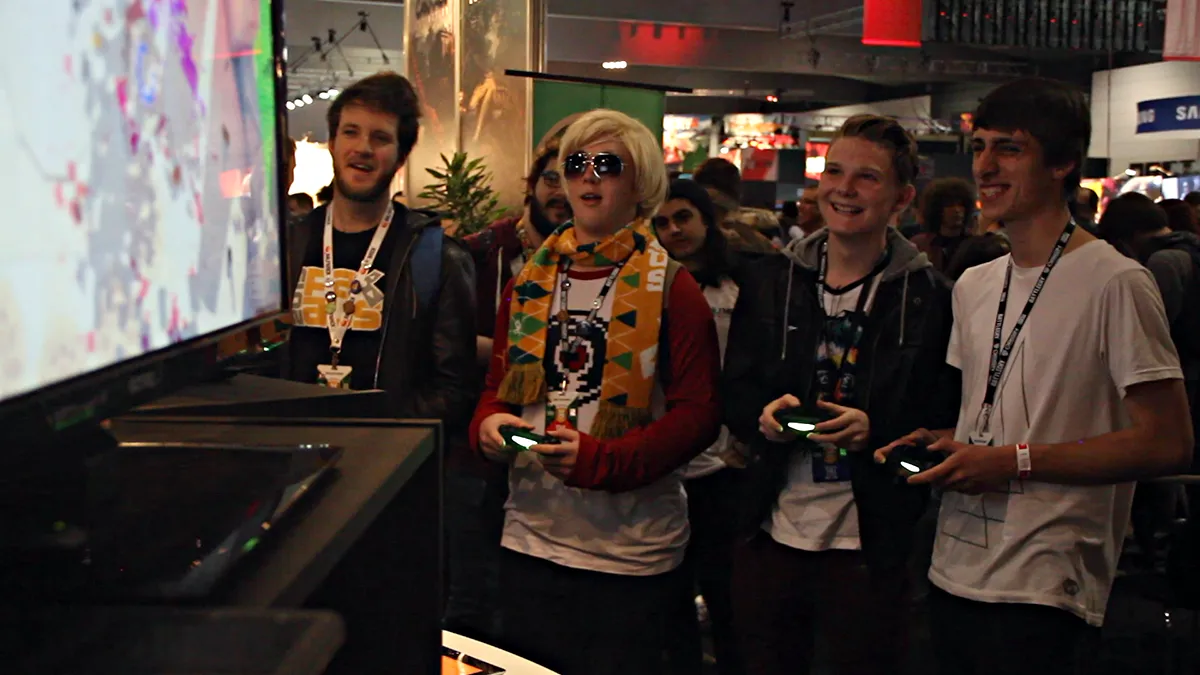 Four PAX attendees playing Swordy with controllers at a crowded booth.