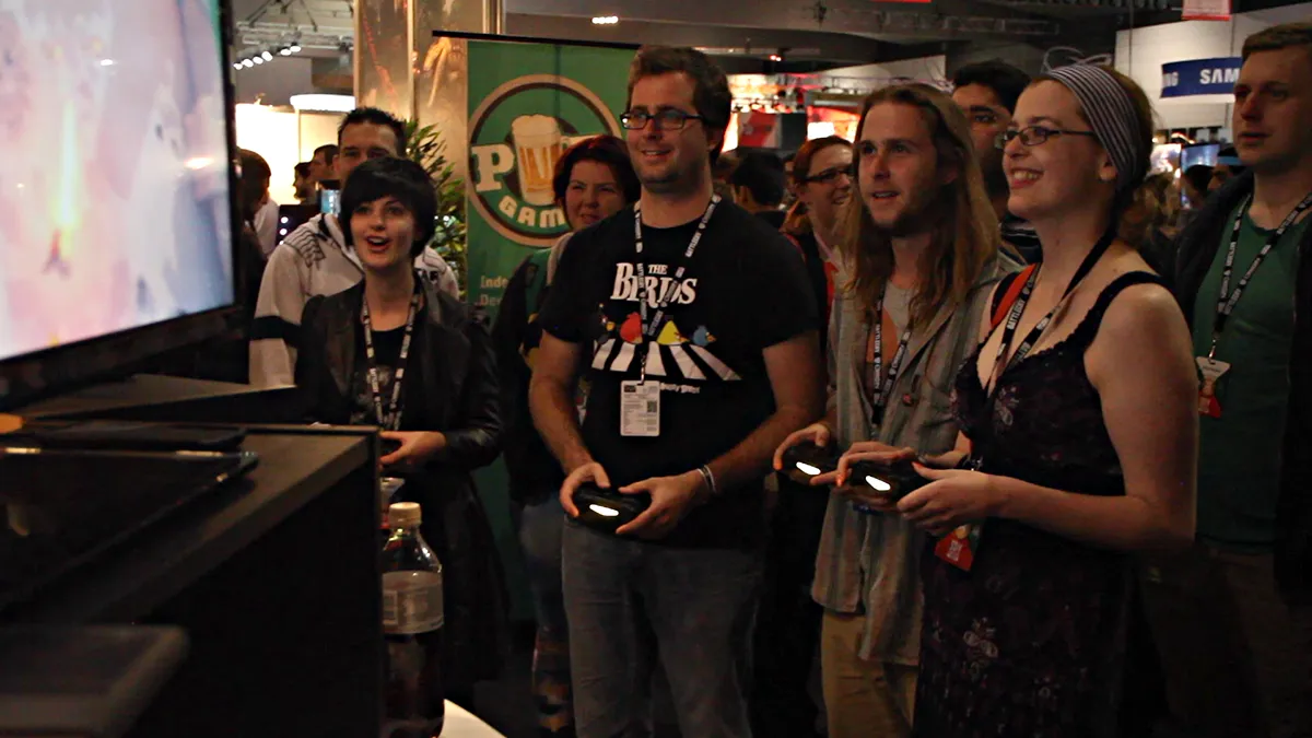 Group of PAX attendees smiling while playing Swordy together at a booth.